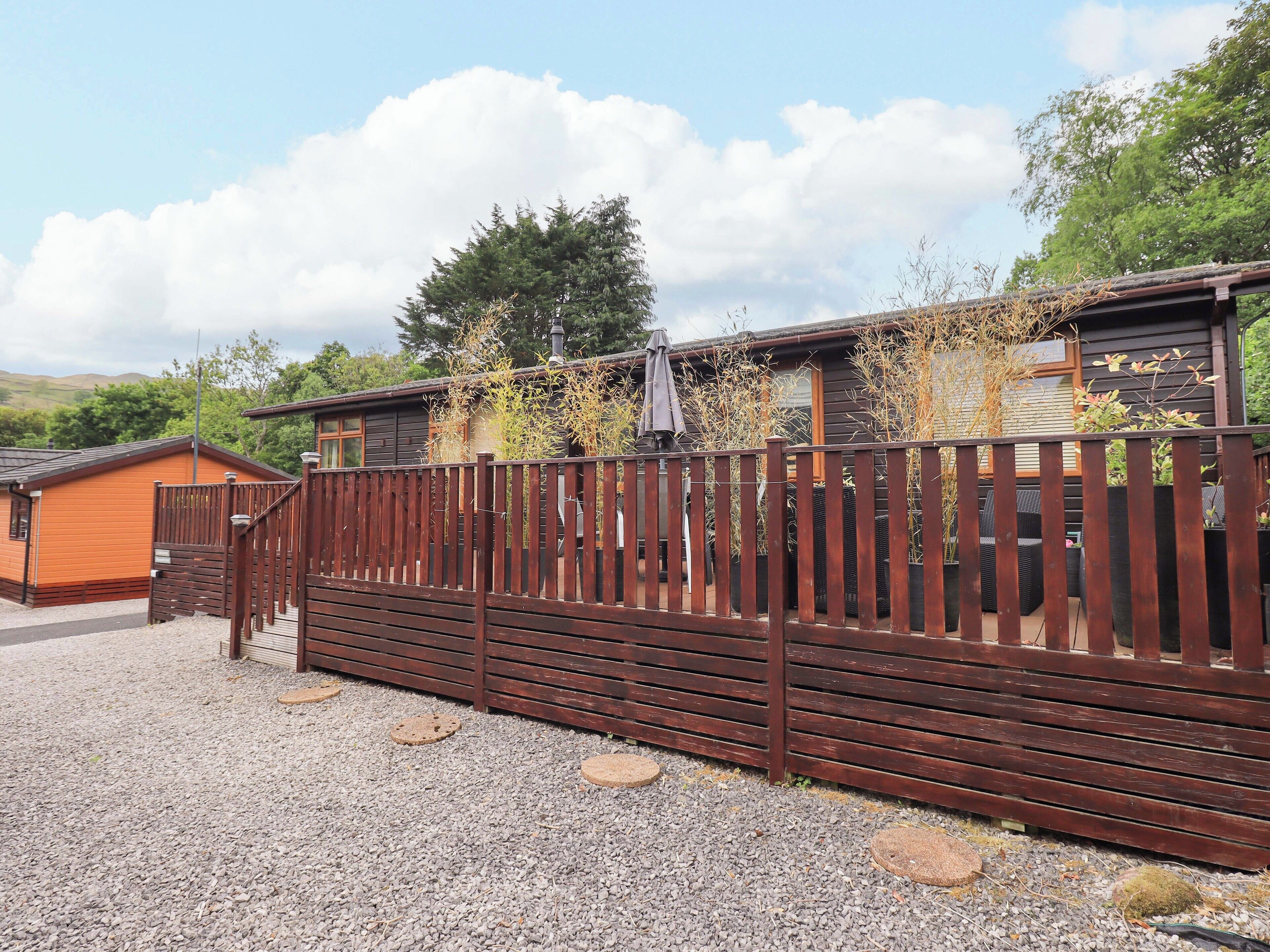 A wooden fence with a gate, a small wooden building, and a larger building with a sloped roof.
