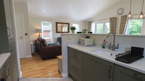 A modern kitchen with a built-in toaster, a sink, and a window with curtains. - Wansfell Retreat Lodge (Windermere)
