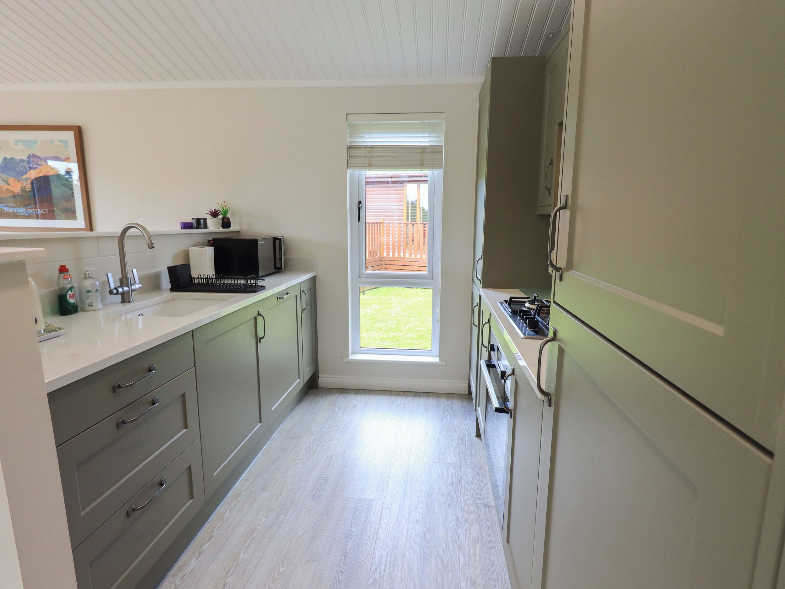 A compact kitchen with a window, a microwave, and a sink.