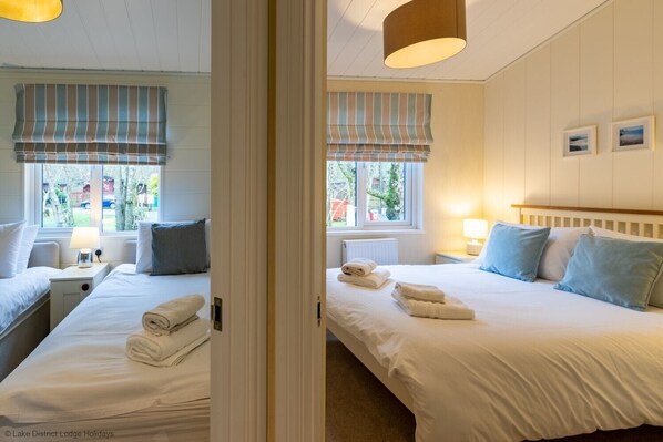 Une chambre d’hôtel avec deux lits, chacun équipé d’un oreiller, d’une table de chevet avec une lampe et d’une fenêtre donnant sur l’extérieur.