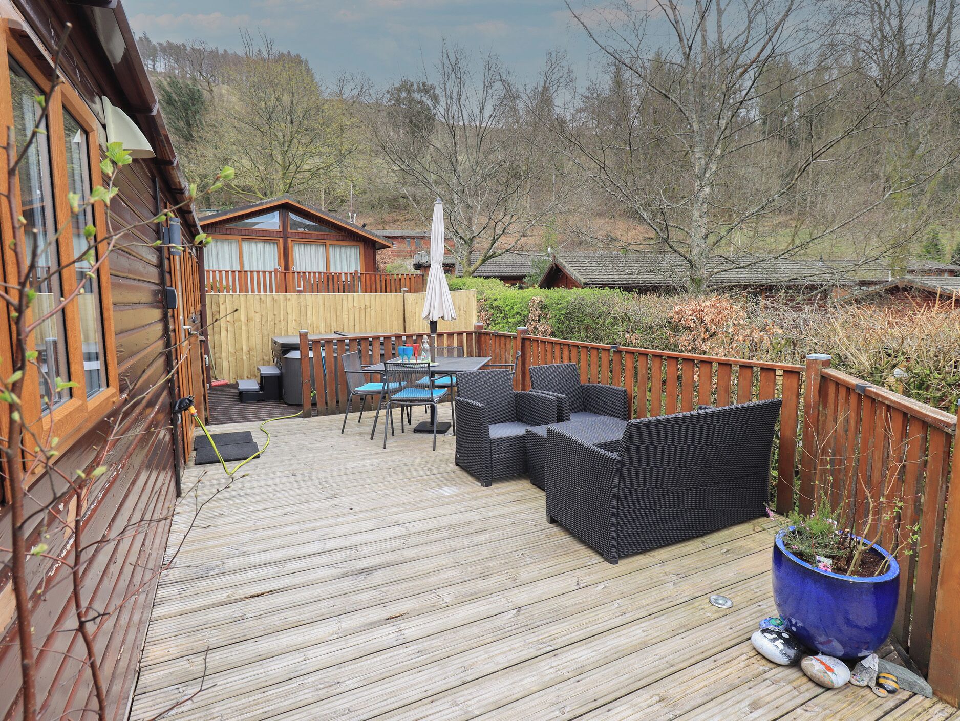 A wooden deck with outdoor furniture, a table, and a potted plant.
