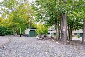 A campground with picnic tables, a shed, and a building with a green door.