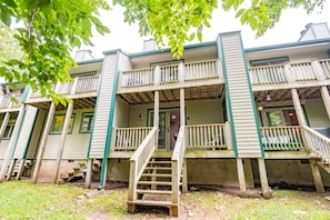 A multi-story building with a porch and a staircase leading to the entrance.