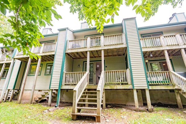 A multi-story building with a porch and a staircase leading to the entrance.