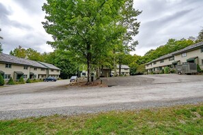 Um bairro residencial com várias casas de dois andares, uma entrada de automóveis de cascalho e uma grande árvore ao centro.