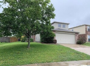 Simple, functional home surrounded by a well-maintained lawn and a mature tree.