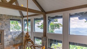 Une pièce dotée de grandes fenêtres, d’une cheminée en pierre et d’un plafond en bois.