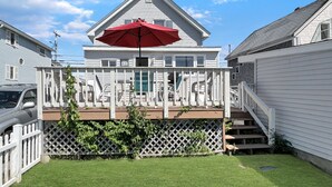 A two-story house with a covered deck and a red umbrella.