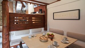 A cozy dining area with a wooden table set for breakfast, a stone wall, and a framed picture on the wall. - Lovely apartment in villa for 6 guests with A/C, WIFI, TV, terrace and pets allowed (Bad Wildungen)