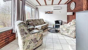 A room with a wooden ceiling, a sofa set, a small table, and a clock on the wall. - Lovely apartment in villa for 6 guests with A/C, WIFI, TV, terrace and pets allowed (Bad Wildungen)
