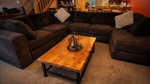 Una sala de estar acogedora con un sofá modular, una mesa de centro de madera y un farol decorativo.