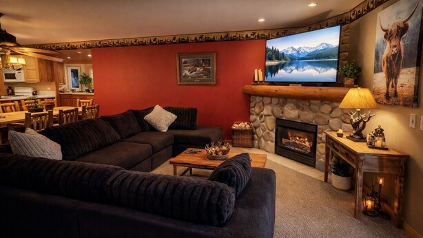 Una sala de estar acogedora con chimenea de piedra, un televisor de pantalla plana grande y un comedor con muebles de madera.