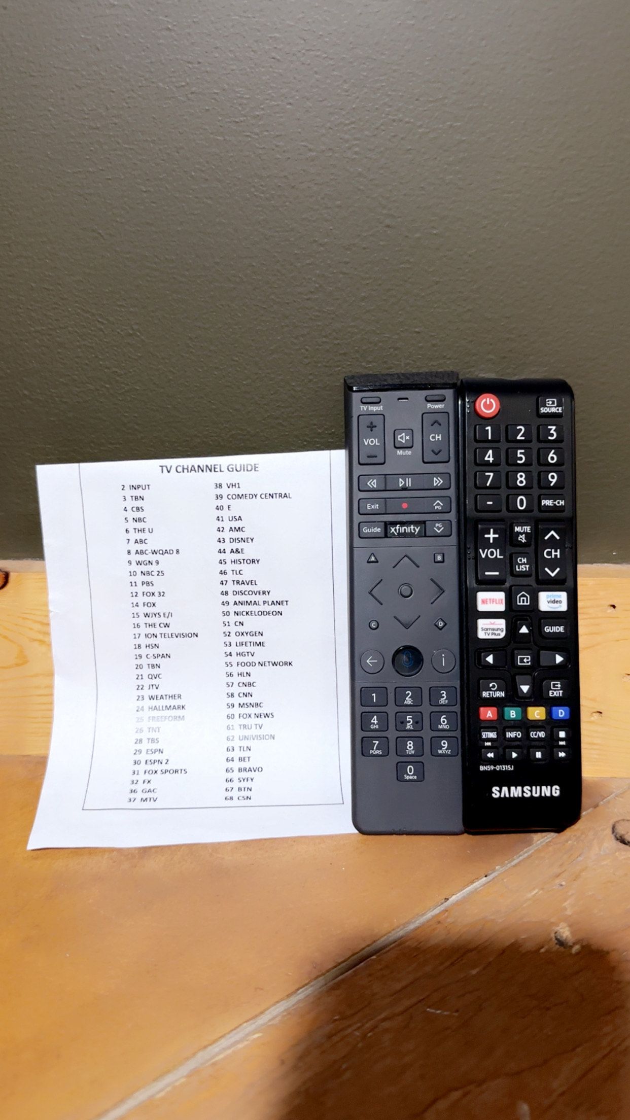 Una guía de canales de televisión y un control remoto Samsung sobre una superficie de madera.