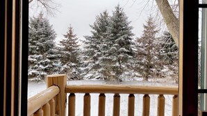 Barandilla de madera con vista a árboles cubiertos de nieve.