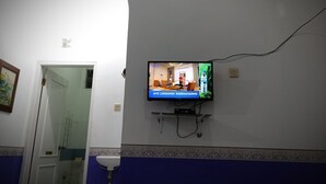A television mounted on a wall in a room with a bathroom sink and a door leading to another room. - Tempat Nginap 2BR Ciater Highland Resort (Ciater)