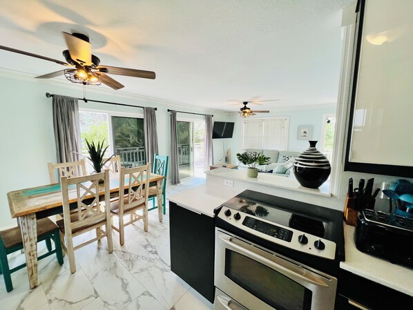 A modern kitchen with a stove, oven, and dining area with a table and chairs.
