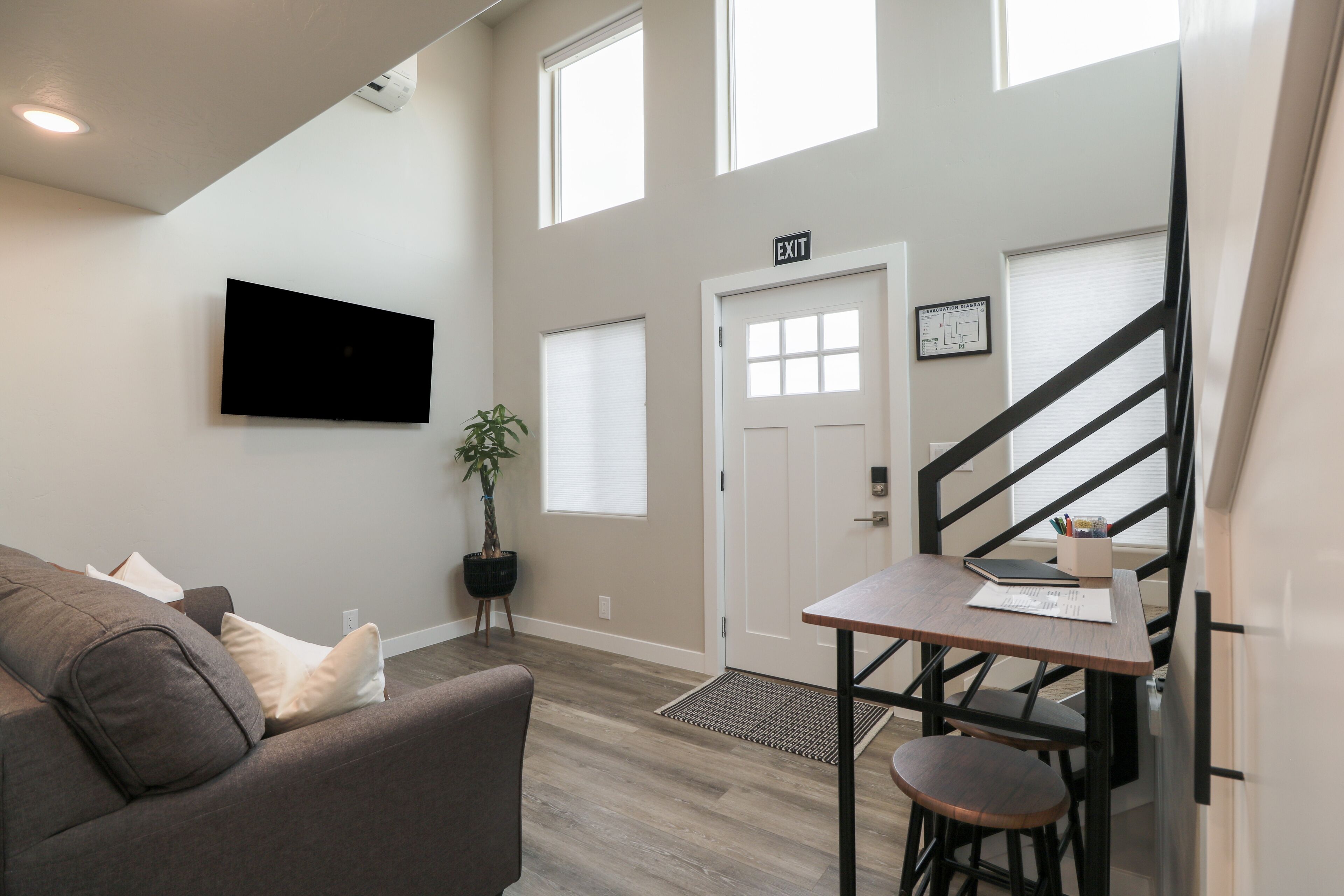 A modern living room with a gray couch, a wooden table, and a staircase leading to an upper level.