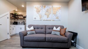 Una sala de estar moderna con un sofá gris, una cafetera y un mapa del mundo en la pared.