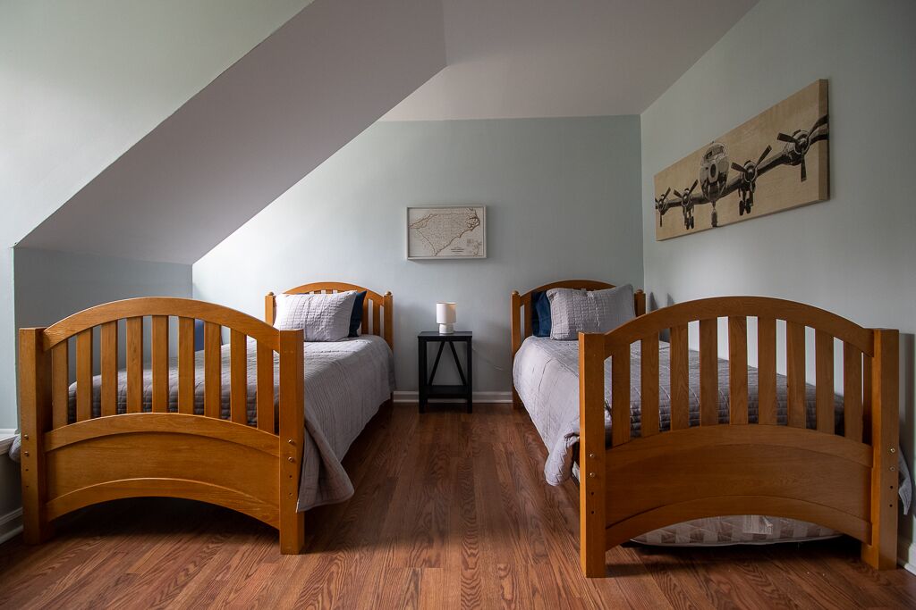 A bedroom with two wooden beds, a small table, and a map on the wall.