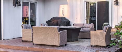 An outdoor patio with wicker furniture, a grill, and a covered table.