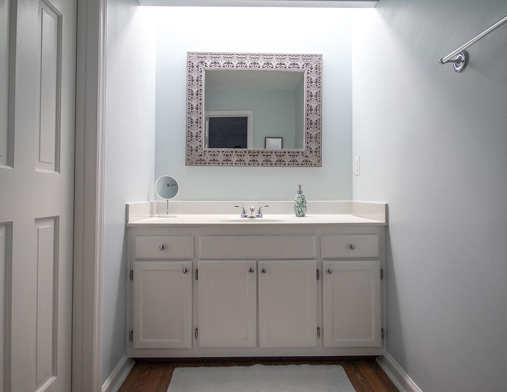 A bathroom with a white vanity, a mirror with a decorative frame, and a shower area.
