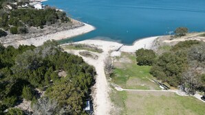 Ein Luftbild zeigt ein Küstenanwesen mit Sandstrand, dichter Bepflanzung und freiem Blick auf den Ozean.