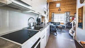 A modern kitchen with a central island, a dining area with a sofa and table, and a wooden interior.