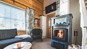 A cozy living room with a fireplace, a sofa, a coffee table, and a TV mounted on the wall.