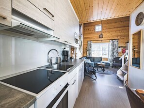 Moderni keittiö, jossa on musta induktioliesi, valkoiset kaapit ja ruostumattomasta teräksestä valmistettu pesuallas.