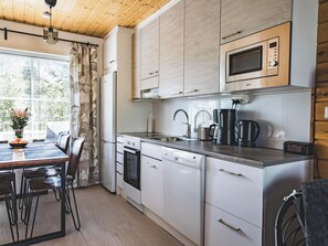 Une cuisine moderne avec des meubles blancs, un four à micro-ondes, une machine à café et un lave-vaisselle.