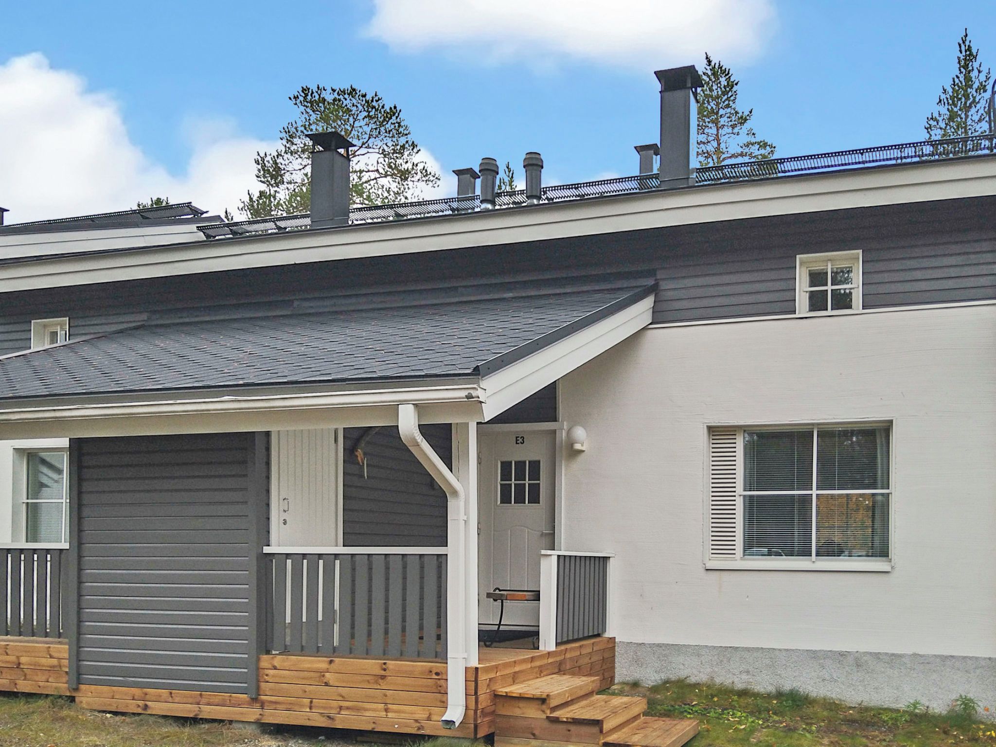 A residential building with a covered porch, a garage, and a chimney.