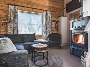 A cozy living room with a fireplace, a sofa, a chair, and a small round table with a candle.