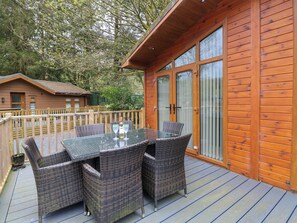 A wooden deck with a glass table and wicker chairs, overlooking a forested area. - Oakwood Lodge (Windermere)