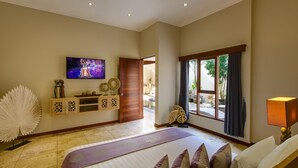Ein geräumiges Schlafzimmer mit einem großen Bett, einem an der Wand befestigten Fernseher und Blick ins Freie durch ein Fenster.