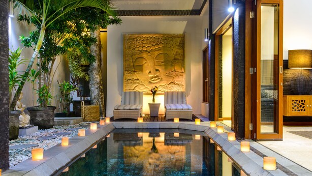 Ein ruhiger Poolbereich im Innenbereich mit Buddha-Statue, Sitzgelegenheiten und Kerzen.