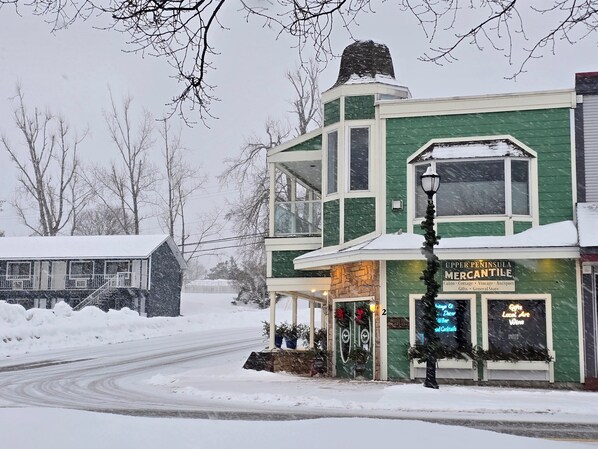 A two-story building with a green facade and a sign for 'Upper Peninsula Mercantile' offering cabin, cottage, vintage, antiques, gifts, and a general store.