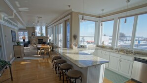 Een ruime keuken met een groot eiland, barkrukken en uitzicht op buiten.