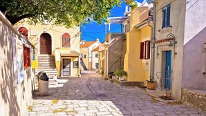 Una calle adoquinada en un pueblo histórico, con edificios que presentan arcos y contraventanas tradicionales.