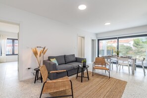 A modern living room with a grey sofa, two wicker chairs, a small table, and a large window offering a view of the outside. - Pool Apartment Sapore Di Mare 1, Baška, Croatia (Baška)