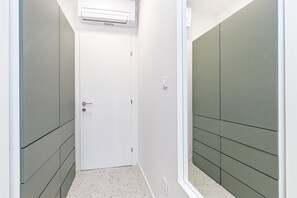 En smal gang med en hvid dør, grå vægge og et hvidt loft med et klimaanlæg.