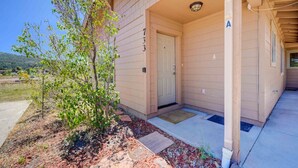 A house with a covered porch, a door, and a small tree. - Grand Canyon Basecamp with EV (Williams)
