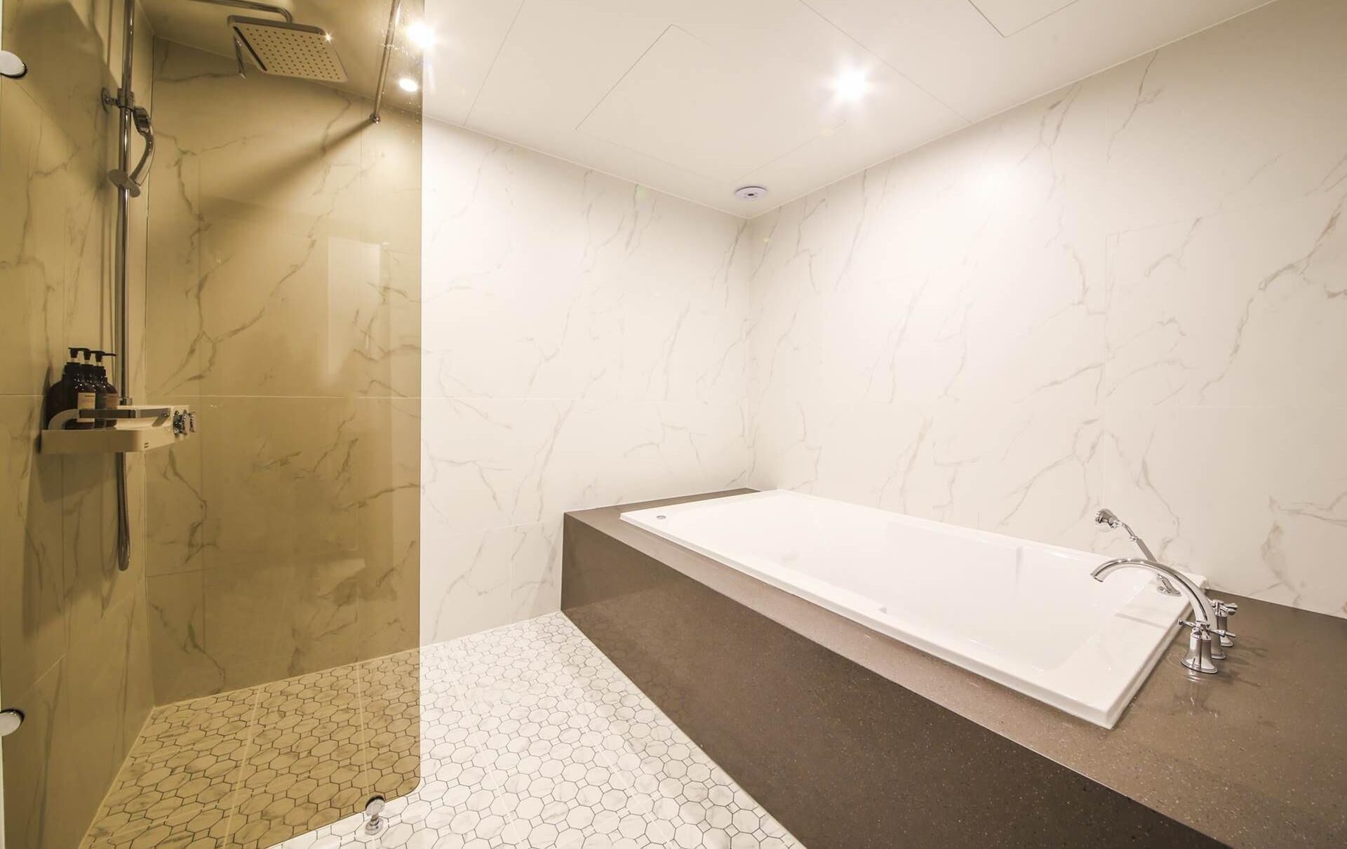 Een moderne badkamer met een inloopdouche, een vrijstaand bad en een wastafel met een grote spiegel.