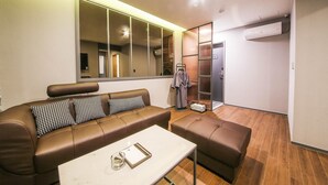 A modern living room with a brown leather sofa, a white coffee table, and a large mirror. - Gupo Brown-Dot Hotel (Busan)