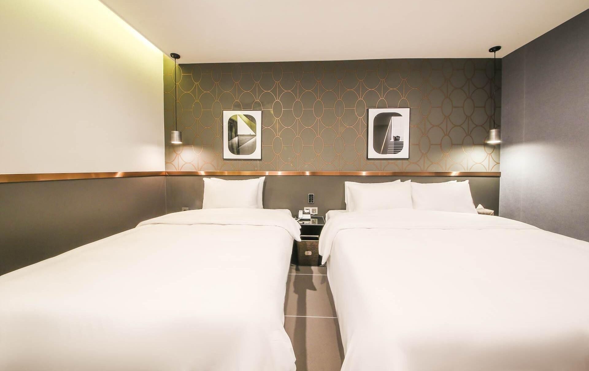 Una habitación de hotel con dos camas, una mesita de noche y un teléfono instalado en la pared.