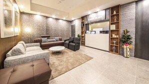 A modern lobby with a reception desk, seating area with sofas and chairs, and decorative elements like plants and wall art. - Gupo Brown-Dot Hotel (Busan)