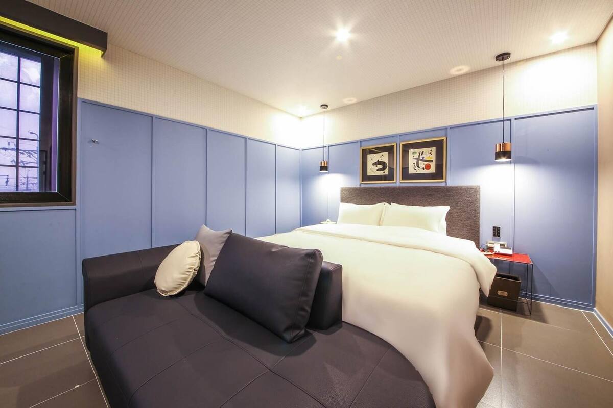Ein modernes Hotelzimmer mit einem Bett, einer Couch und einem Nachttisch.