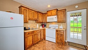 A kitchen with wooden cabinets, a white refrigerator, a microwave, a stove, and a sink.