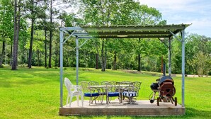 A gazebo with a table and chairs in a grassy park area.