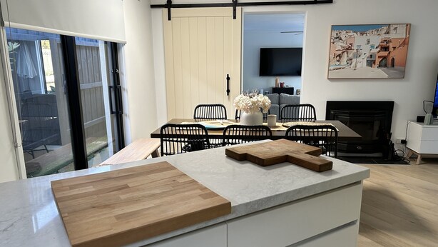 A modern kitchen with a large island, black chairs, a dining table, and a fireplace. - Welcome to Rose on Rye, your private oasis.<br> (Rye)