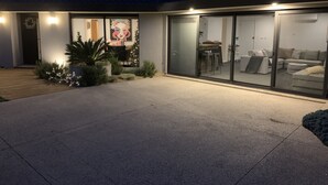 A modern house with a patio, a large glass sliding door leading to a living area, and a Christmas tree. - Welcome to Rose on Rye, your private oasis.<br> (Rye)